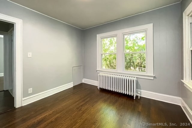 empty room with dark wood-type flooring and radiator