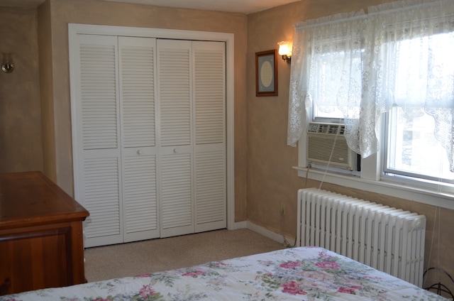 carpeted bedroom with cooling unit, a closet, and radiator