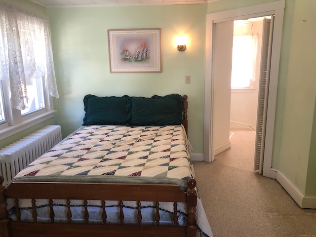 carpeted bedroom with a closet and radiator