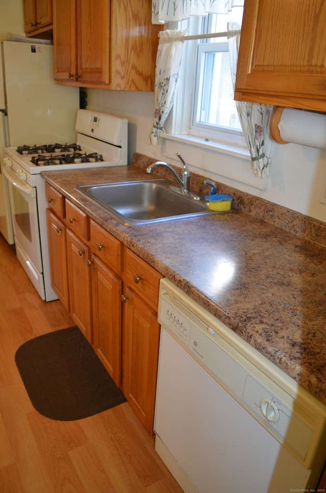 kitchen with sink, light wood-type flooring, and white appliances