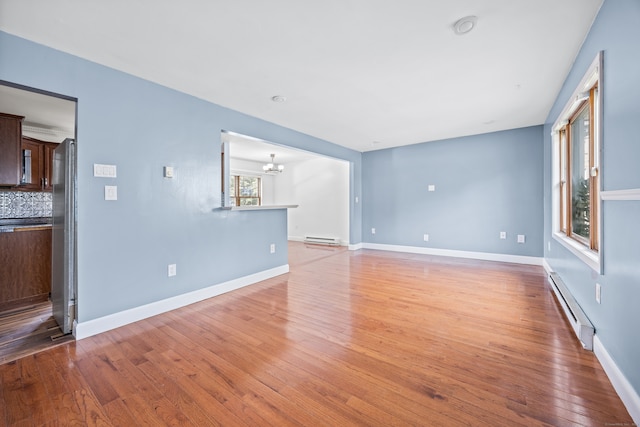 unfurnished living room featuring a notable chandelier, wood-type flooring, and a baseboard radiator