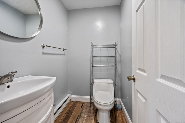 bathroom featuring vanity, toilet, hardwood / wood-style flooring, and a baseboard heating unit