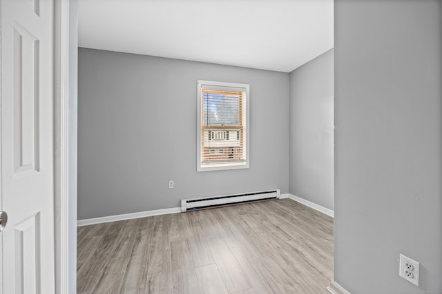 unfurnished room featuring baseboard heating and light wood-type flooring