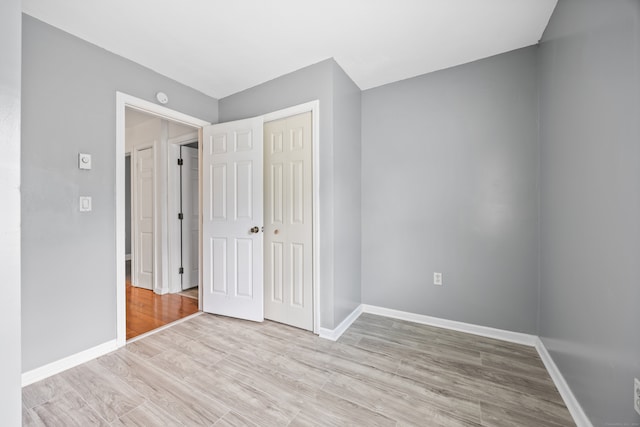 unfurnished bedroom with a closet and light wood-type flooring