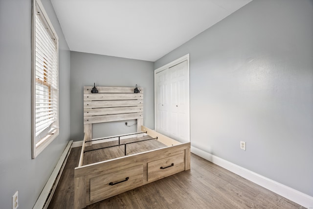 bedroom with a closet, hardwood / wood-style flooring, and a baseboard radiator