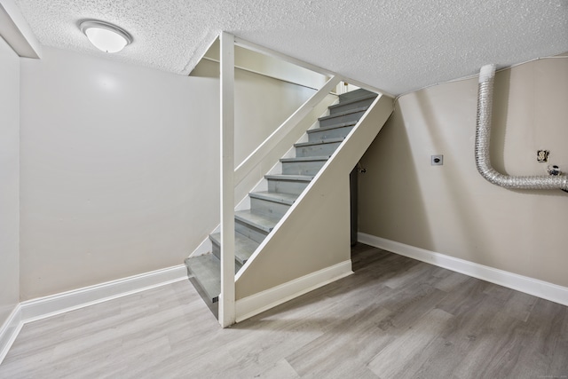 stairs featuring wood-type flooring and a textured ceiling