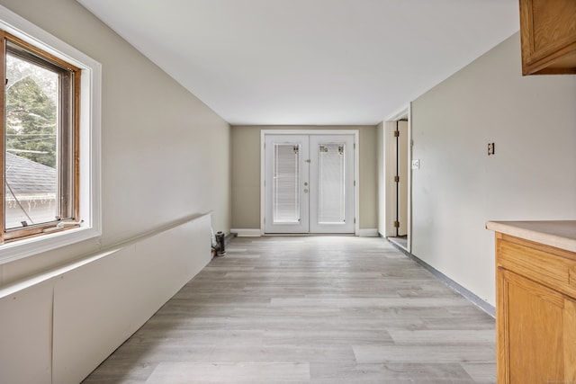 corridor with french doors and light hardwood / wood-style floors