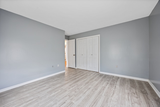 unfurnished bedroom featuring light hardwood / wood-style flooring and a closet