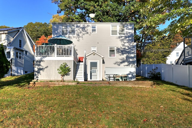 back of property featuring a deck and a lawn