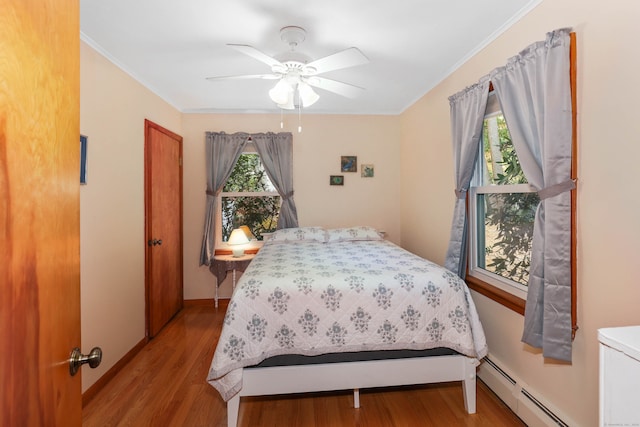 bedroom featuring crown molding, a baseboard heating unit, light wood-type flooring, and ceiling fan