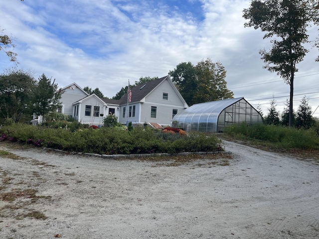 view of front of property with an outdoor structure and a greenhouse