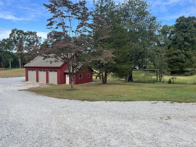 view of yard with an outdoor structure, driveway, and a detached garage