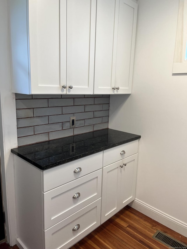 kitchen with dark stone countertops, white cabinets, tasteful backsplash, and dark hardwood / wood-style flooring