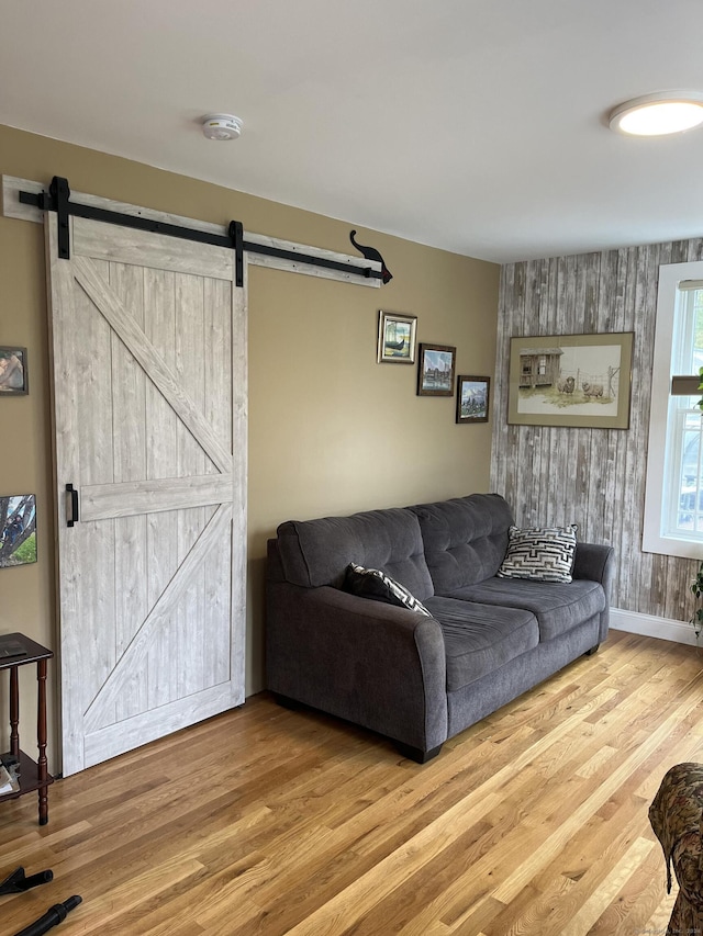 living area featuring baseboards, a barn door, and wood finished floors