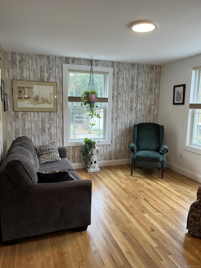 living area with hardwood / wood-style flooring, a wealth of natural light, and wood walls