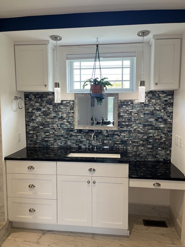 kitchen featuring white cabinetry, tasteful backsplash, sink, and hanging light fixtures