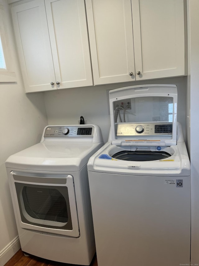 clothes washing area featuring independent washer and dryer, dark wood-style flooring, and cabinet space