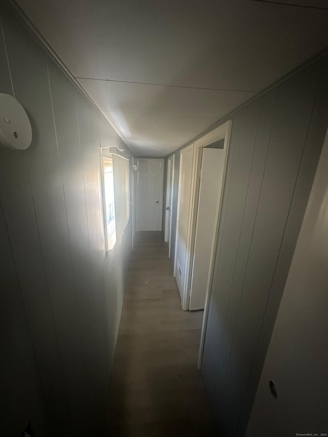 corridor with light hardwood / wood-style floors and wood walls