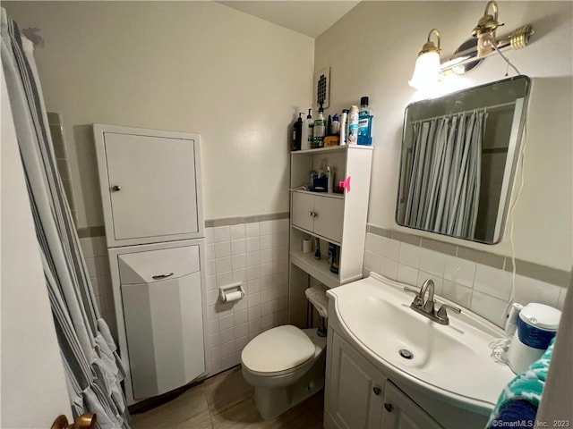 bathroom with toilet, vanity, tile patterned floors, and tile walls