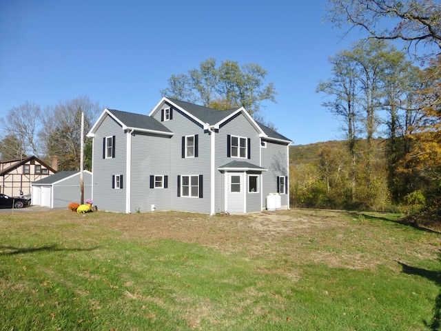 rear view of house featuring a yard, a garage, and an outdoor structure