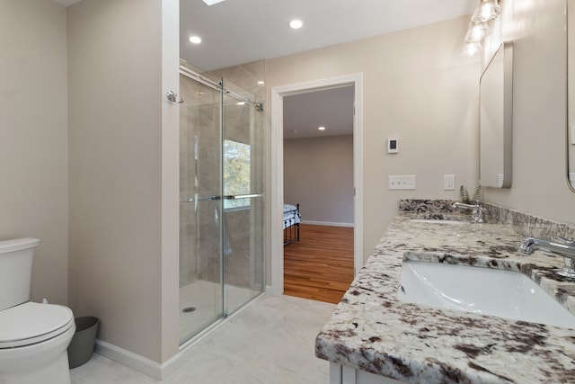 bathroom featuring wood-type flooring, vanity, toilet, and a shower with door