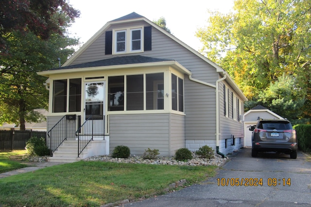 bungalow featuring a front yard, a garage, and an outdoor structure