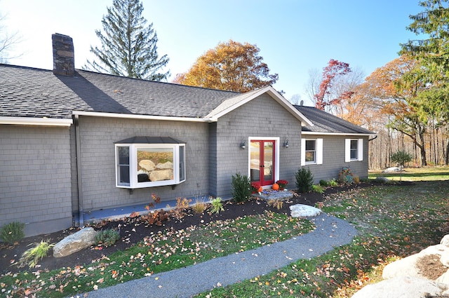 ranch-style home with a shingled roof, french doors, and a chimney