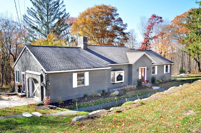 single story home featuring a garage, a shingled roof, a chimney, and a front lawn