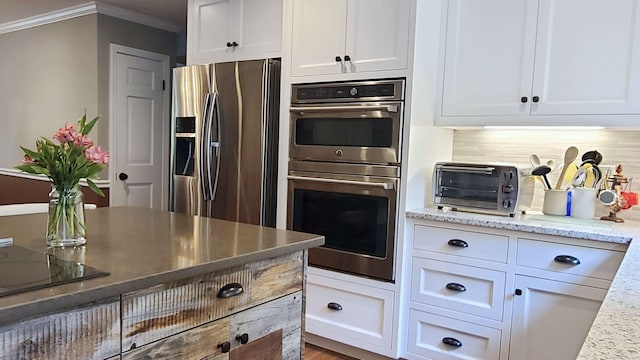 kitchen with crown molding, appliances with stainless steel finishes, white cabinetry, light stone counters, and decorative backsplash