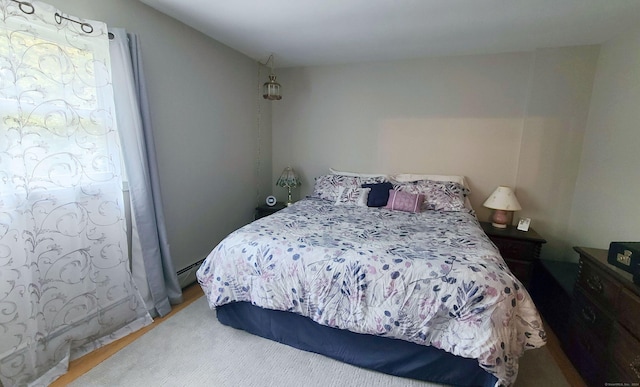 bedroom with a baseboard heating unit and hardwood / wood-style floors