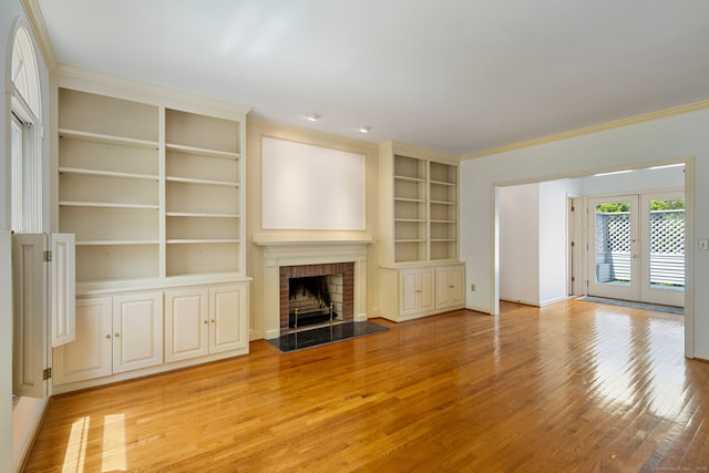 unfurnished living room featuring french doors, light wood-type flooring, a fireplace, and built in shelves