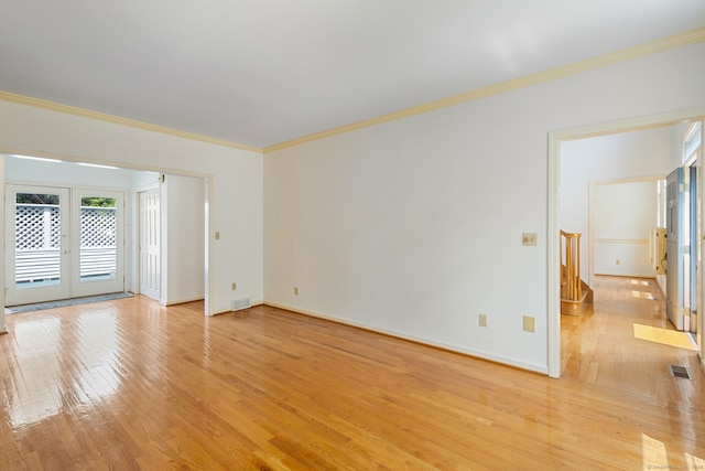 empty room with ornamental molding, french doors, and light hardwood / wood-style floors