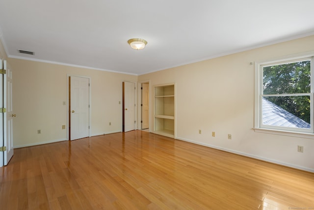 unfurnished bedroom with light hardwood / wood-style floors, crown molding, and two closets