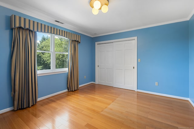 unfurnished bedroom with a closet, ornamental molding, and hardwood / wood-style floors