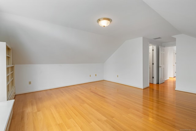 additional living space featuring light hardwood / wood-style floors and vaulted ceiling