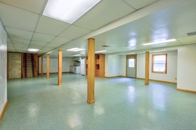 basement featuring a paneled ceiling and white refrigerator