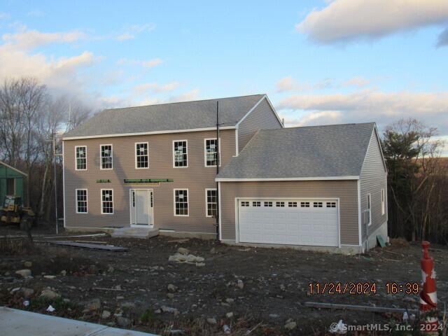 colonial home featuring dirt driveway and an attached garage