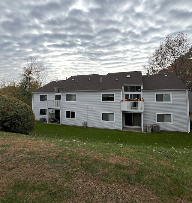 back of house featuring a yard, a balcony, and central air condition unit