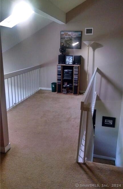 additional living space featuring lofted ceiling with beams and carpet floors