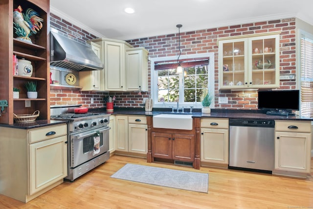 kitchen with stainless steel appliances, wall chimney exhaust hood, sink, and cream cabinets