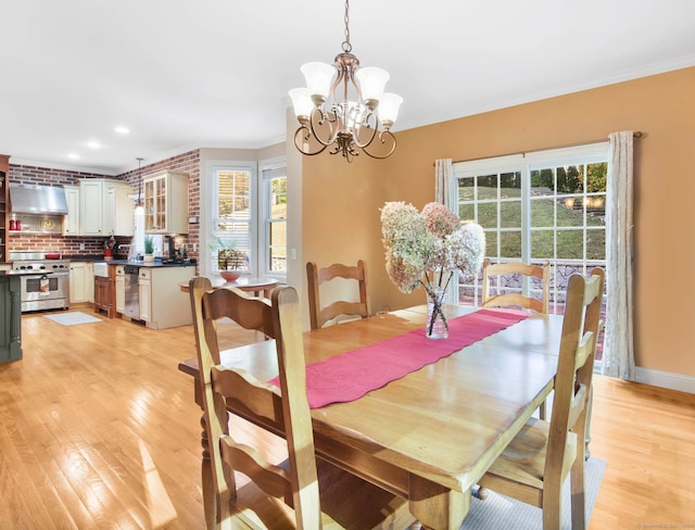 dining room featuring a wealth of natural light, crown molding, light hardwood / wood-style flooring, and an inviting chandelier