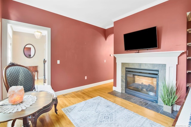 living room featuring light hardwood / wood-style floors, ornamental molding, and a fireplace