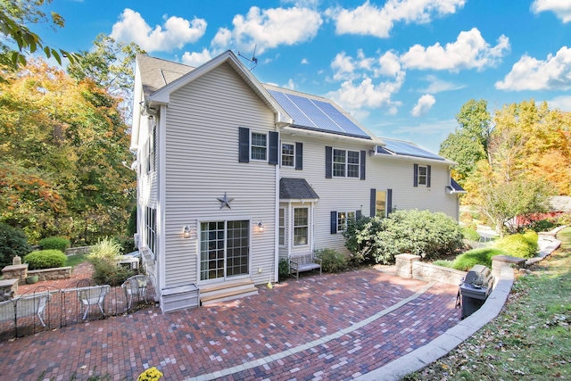 rear view of property with a patio and solar panels