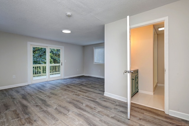 unfurnished room with a textured ceiling and wood-type flooring