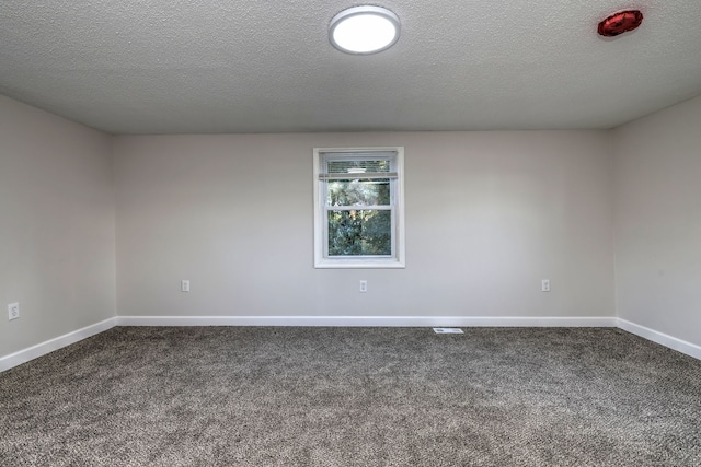 empty room featuring a textured ceiling and dark colored carpet