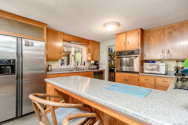 kitchen featuring kitchen peninsula, stainless steel appliances, sink, and a breakfast bar area