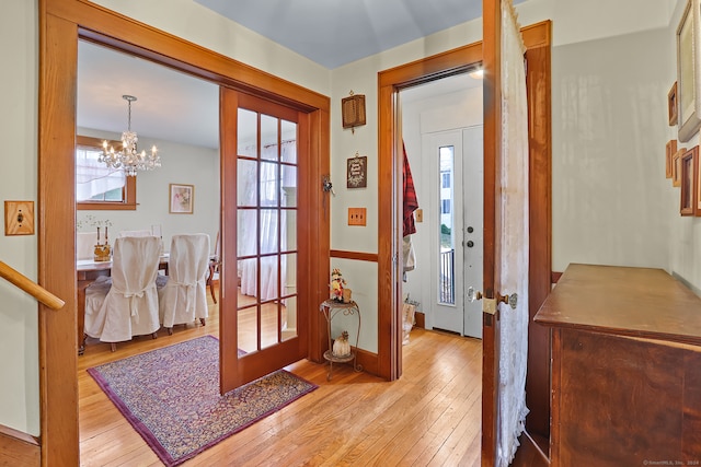 doorway to outside with an inviting chandelier, french doors, and light hardwood / wood-style floors