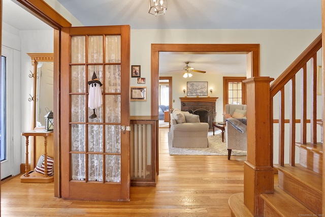 interior space featuring light hardwood / wood-style flooring, a brick fireplace, and ceiling fan