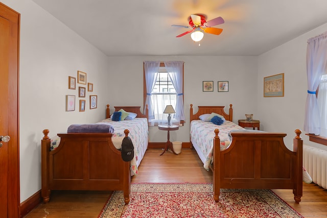 bedroom with radiator, light hardwood / wood-style floors, and ceiling fan