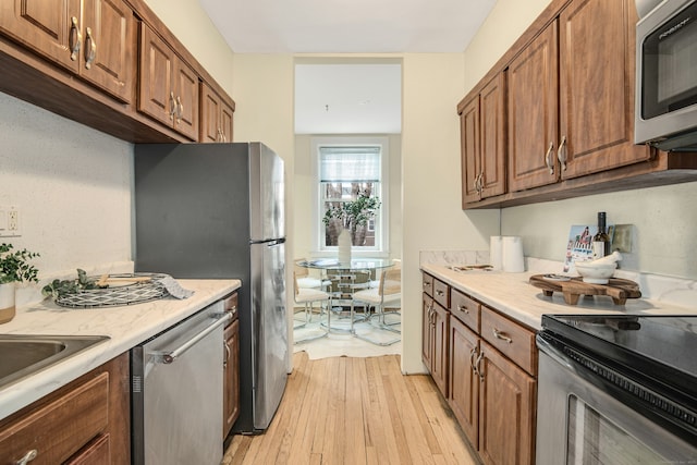 kitchen featuring stainless steel appliances, sink, and light hardwood / wood-style floors